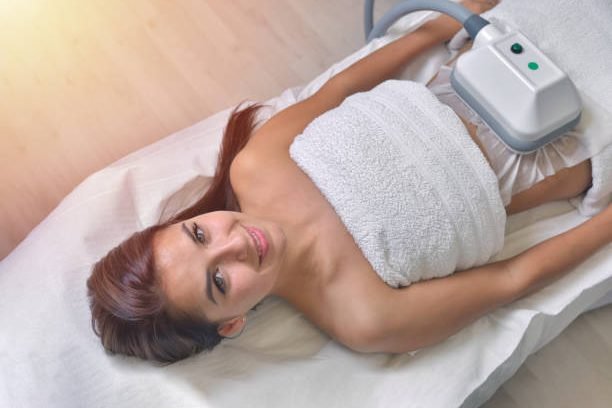 Beautiful young woman getting cryolipolyse treatment in cosmetic cabinet
